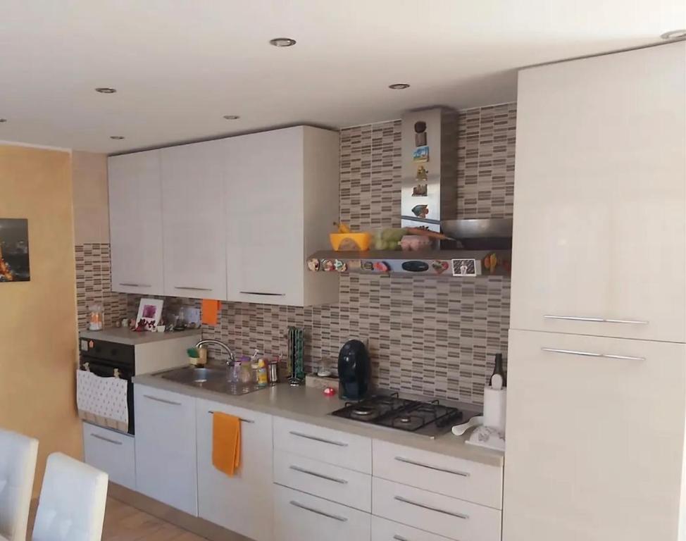 uma cozinha com armários brancos e uma parede de tijolos em NICE APARTMENT VERy MODERN em Caltanissetta