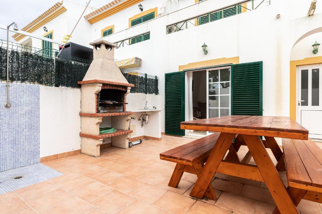 un patio con una mesa de madera y un horno de pizza en Villa Oriente by ALGARVEMANTA, en Manta Rota