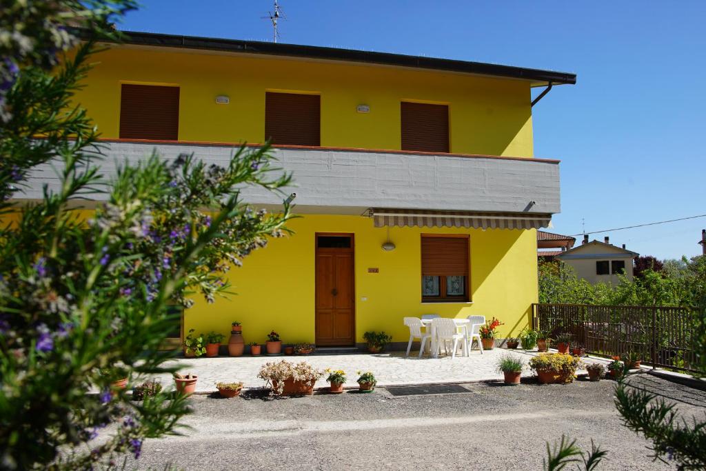 uma casa amarela com uma mesa e cadeiras em frente em Casa Gli Ulivi em Montepulciano