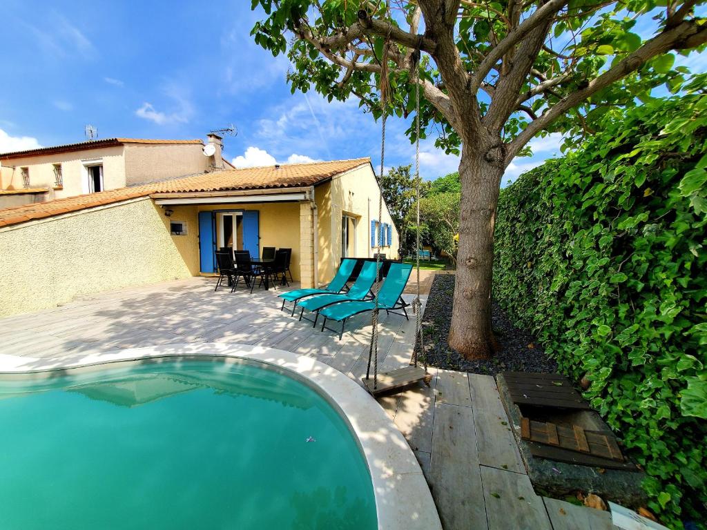 una piscina con tumbonas y un árbol en Villa du soleil, piscine, à 10 mins de Montpellier, en Vendargues