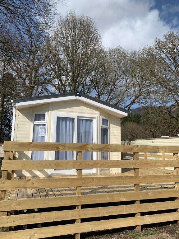 ein kleines gelbes Haus hinter einem Holzzaun in der Unterkunft 36 Glenfinart Caravan Park in Dunoon