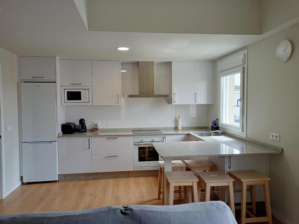 a kitchen with white cabinets and a table and chairs at APARTAMENTO A CASIÑA in Cangas de Morrazo