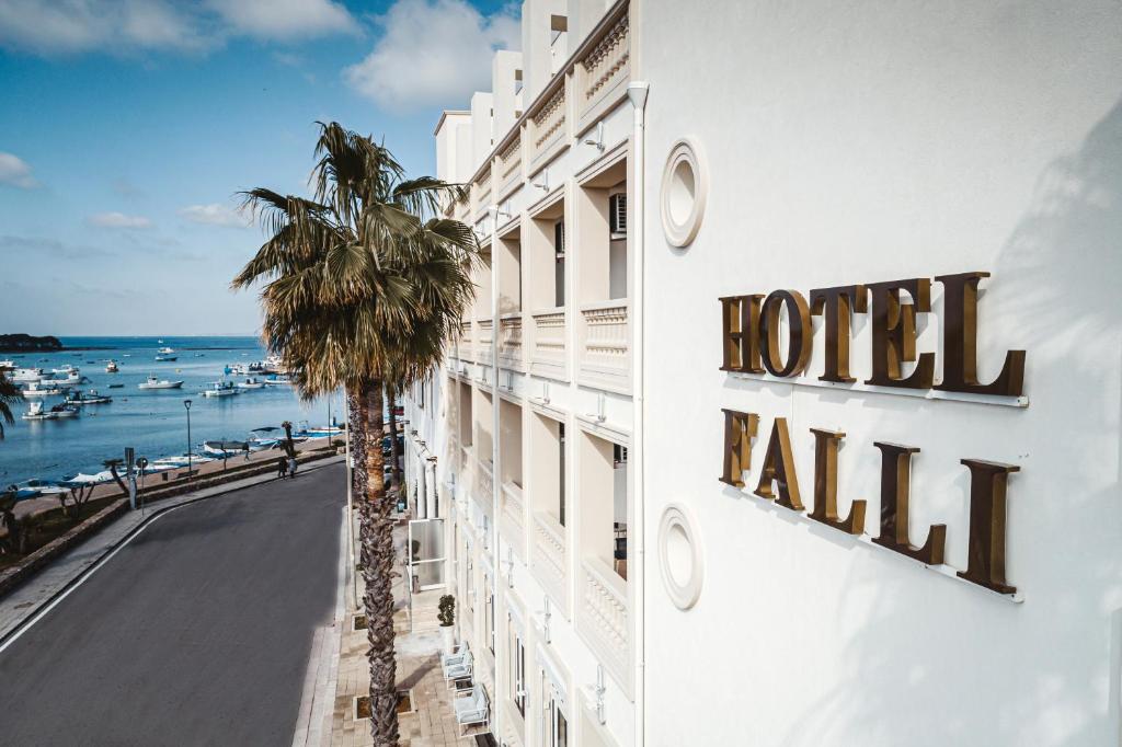 a hotel with a palm tree next to a building at Hotel Falli in Porto Cesareo