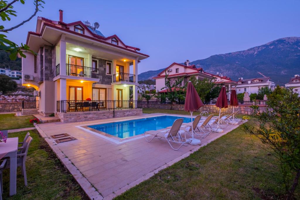 a villa with a swimming pool in front of a house at Infinity Opal Villa in Oludeniz
