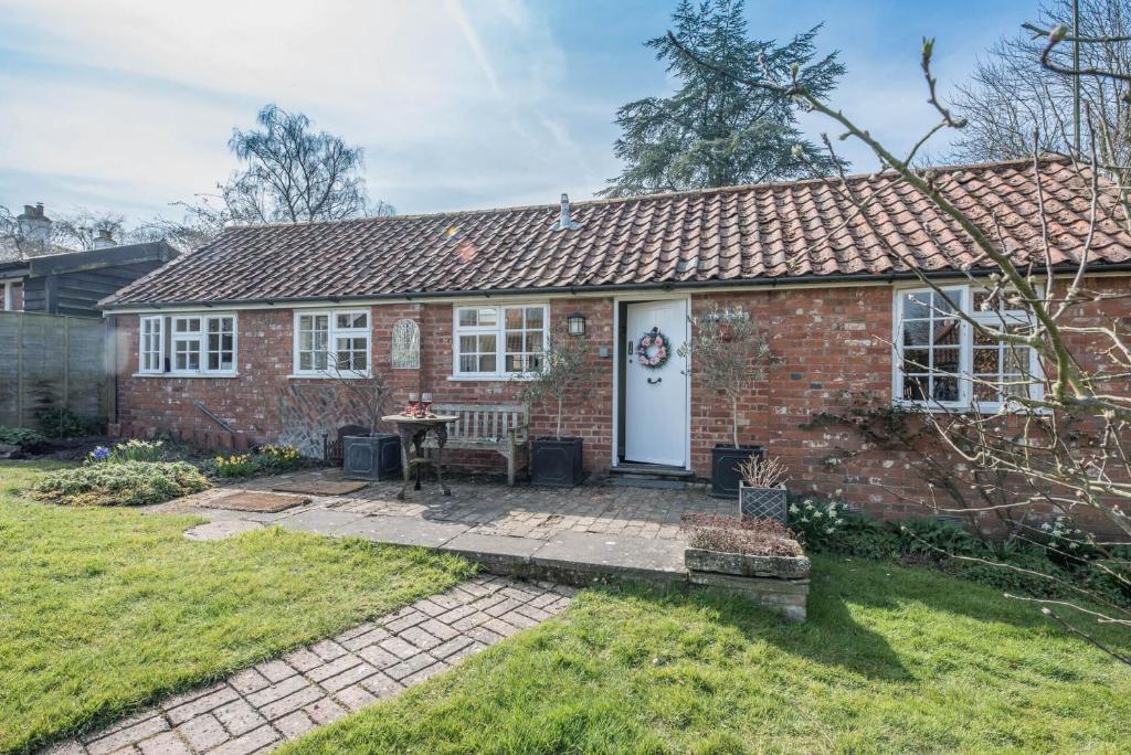a brick house with a white door and a patio at The Stable Grundisburgh Air Manage Suffolk in Woodbridge