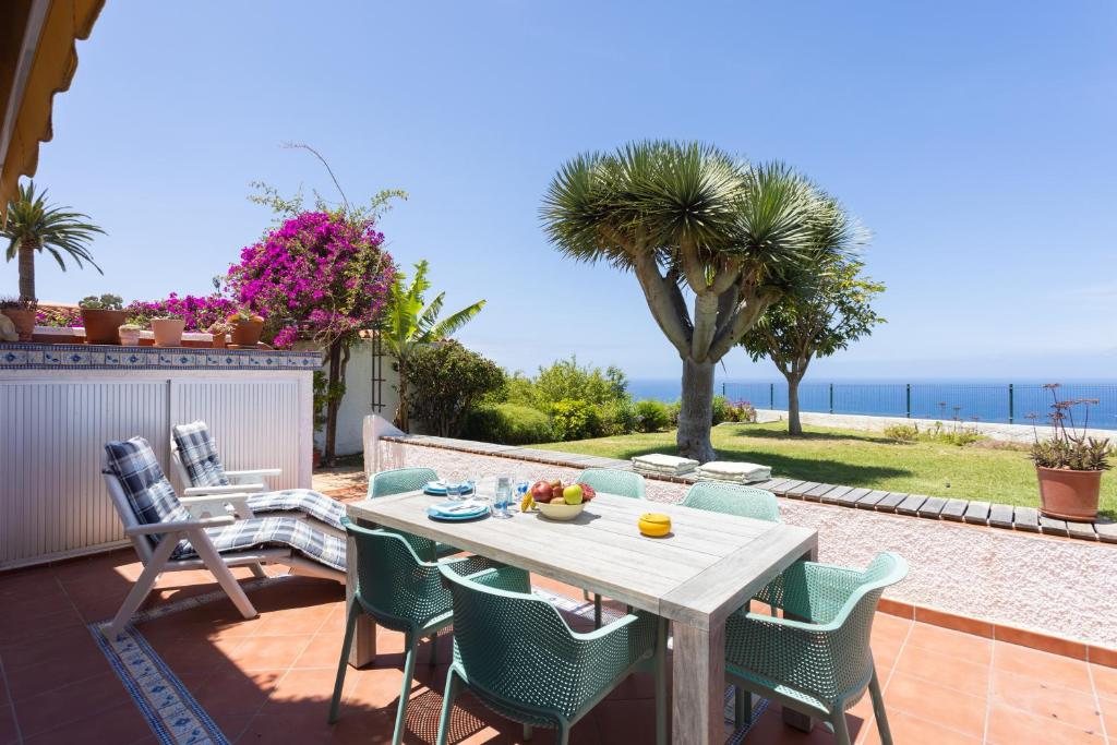 una mesa y sillas en un patio con vistas al océano en Home2Book Amazing La Palmita Suite, en La Victoria de Acentejo