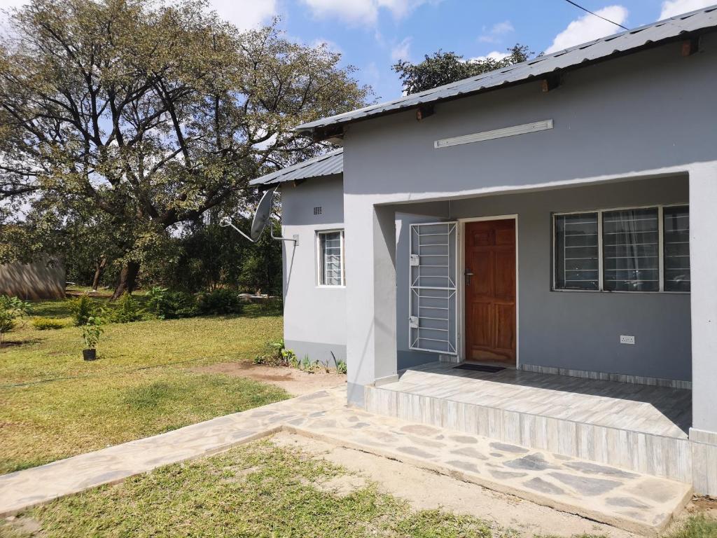 a white house with a brown door and a yard at Sheila's Cottage in Lusaka