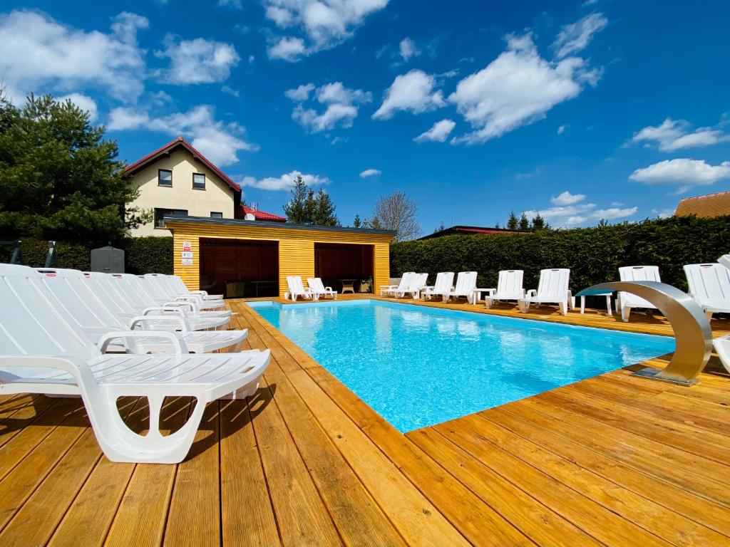 a pool with white lounge chairs on a wooden deck at Mikołajek in Jarosławiec