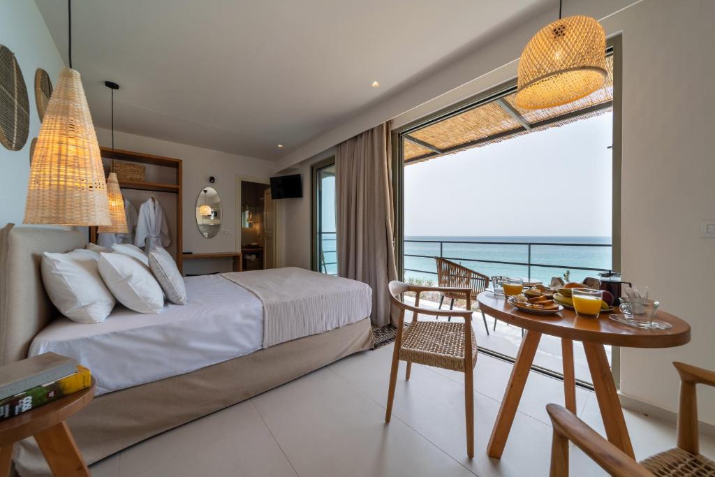 a bedroom with a bed and a table and a window at Thea Suites in Lourdhata