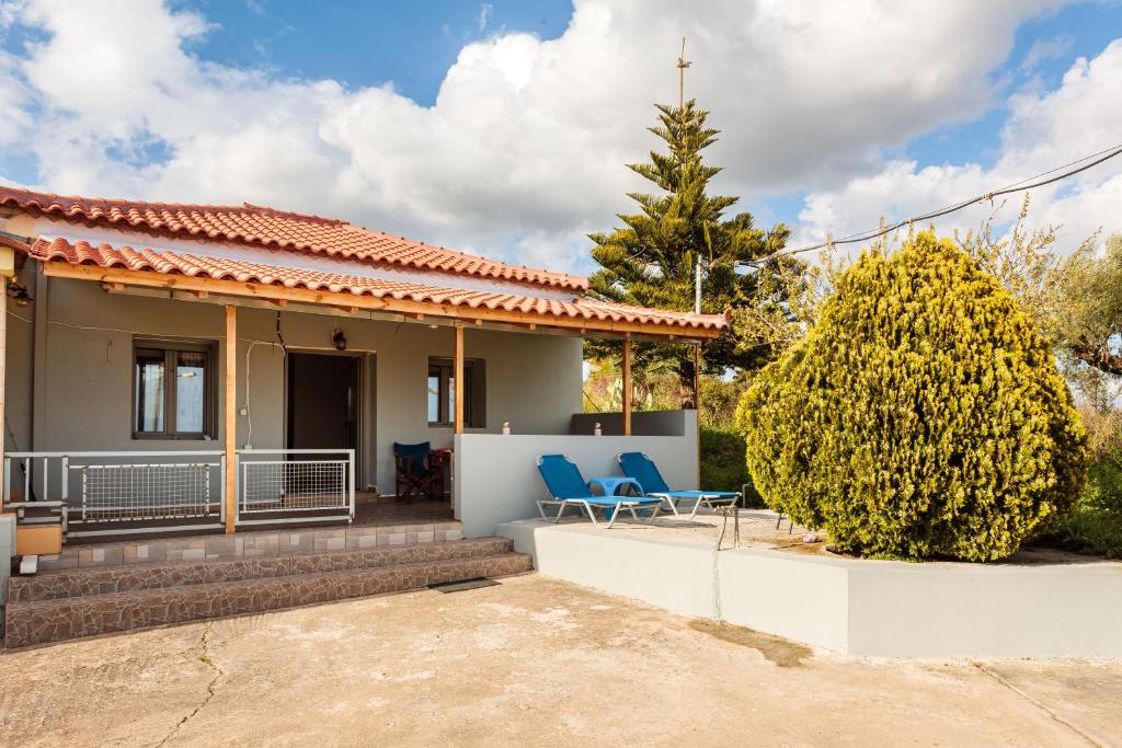 a house with two blue chairs in front of it at Makarounis Athanasios Traditional Apartments(Ξενώνας) in Petalidhion