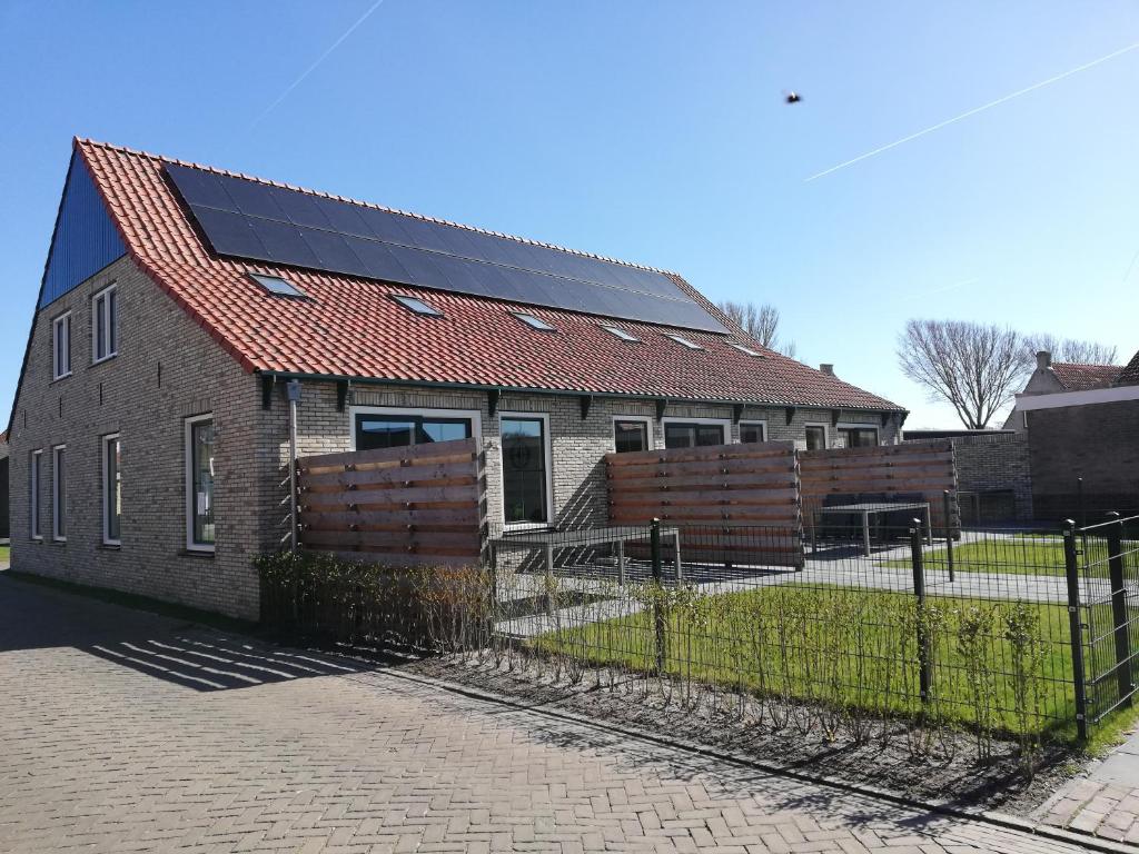 una casa con paneles solares encima en Paardenstal en Hollum