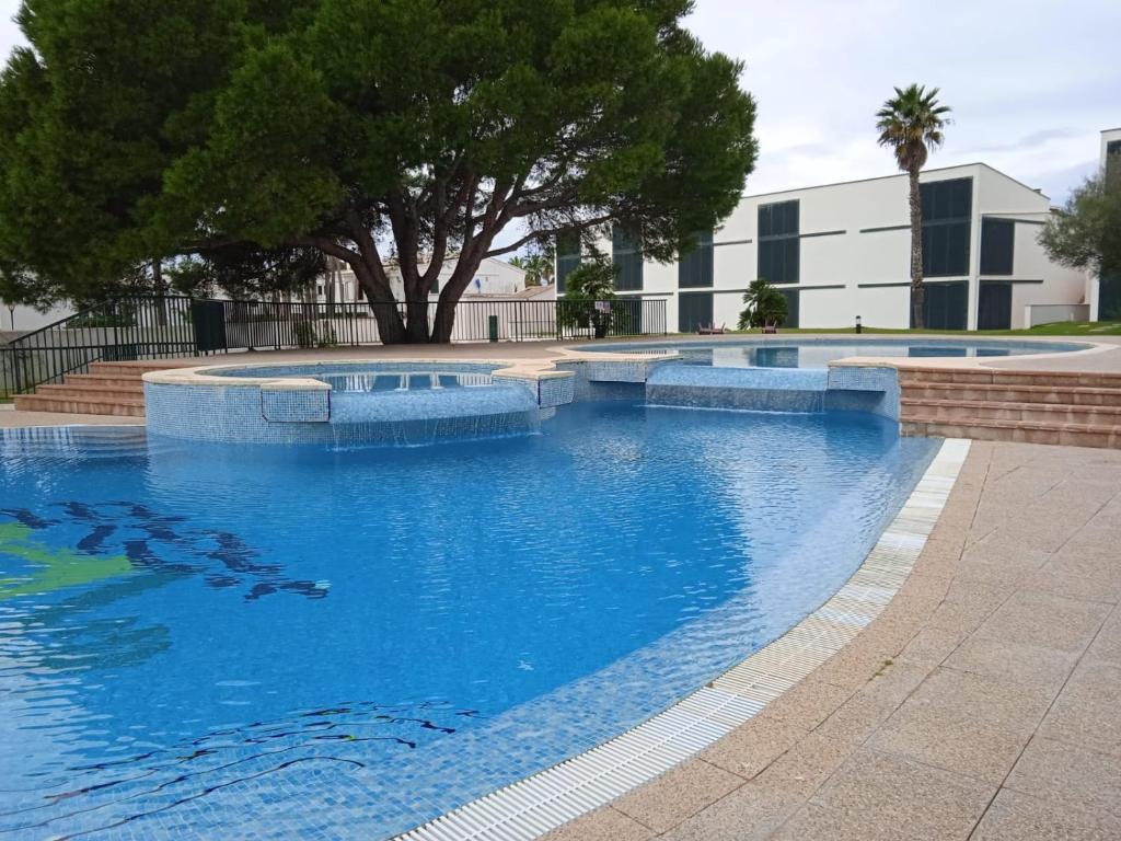 a large swimming pool with blue water in front of a building at Cala´n Bosch in Cala en Bosc