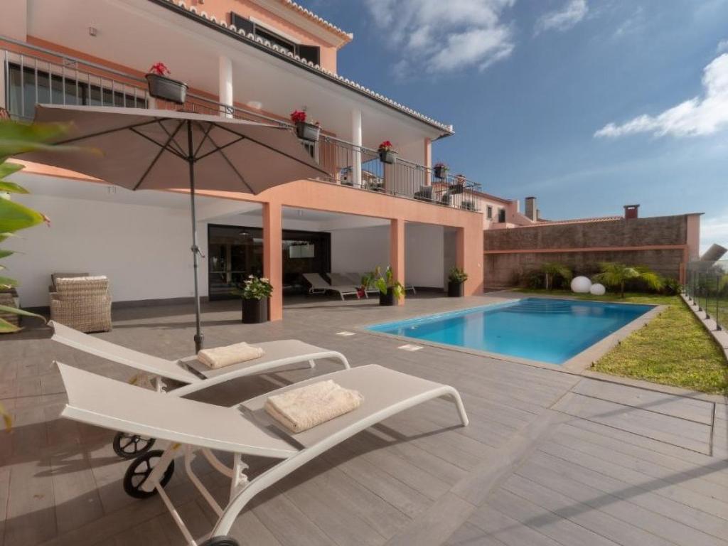 a patio with chairs and an umbrella and a swimming pool at Villa Vacuna in Funchal