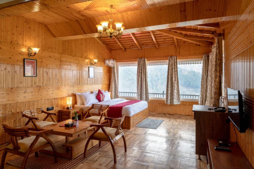 a bedroom with a bed and a table and chairs at ROSASTAYS Vatika - Mountain View in Rāmgarh