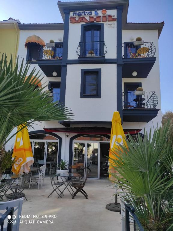 a building with chairs and umbrellas in front of it at Marina Sahil Hotel in Çeşme