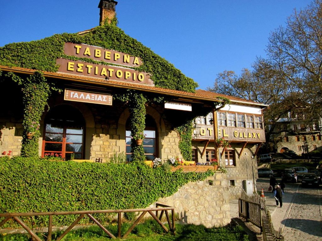 a building covered in ivy with a sign on it at Hotel Galaxias in Metsovo