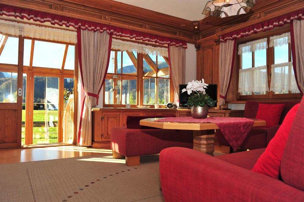 uma sala de estar com cadeiras vermelhas, uma mesa e janelas em Bergpanorama em Oberstdorf