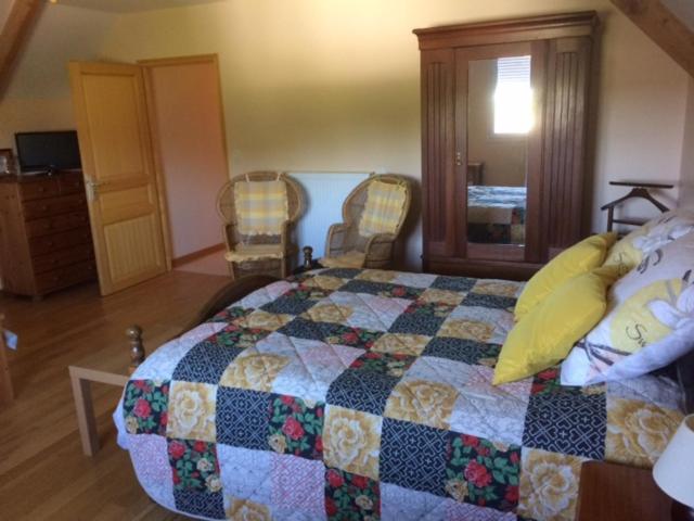a bedroom with a quilt on a bed with two chairs at Les petits chenes in La Pellerine