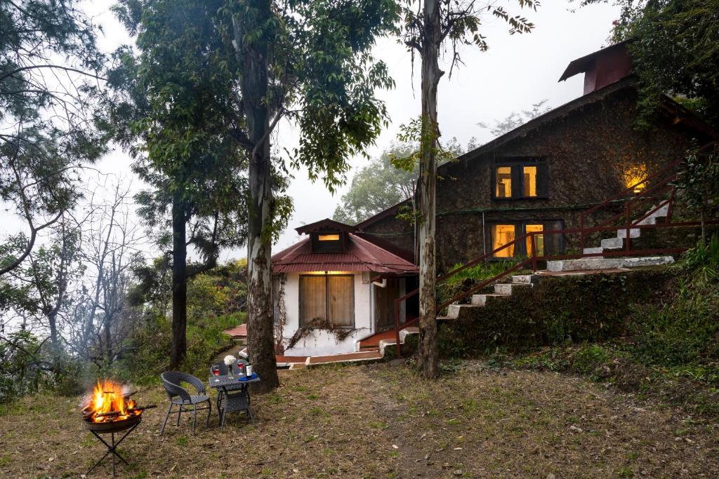 una casa en el bosque con un fuego delante de ella en ROSASTAYS Jeolikote en Nainital