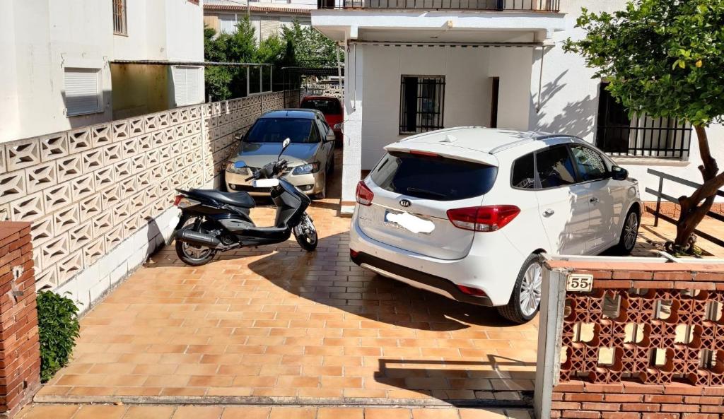 une voiture blanche et un scooter garés à côté d'une maison dans l'établissement Casa CHALET INDEPENDIENTE en CALLE PRIVADA, à Los Mártires