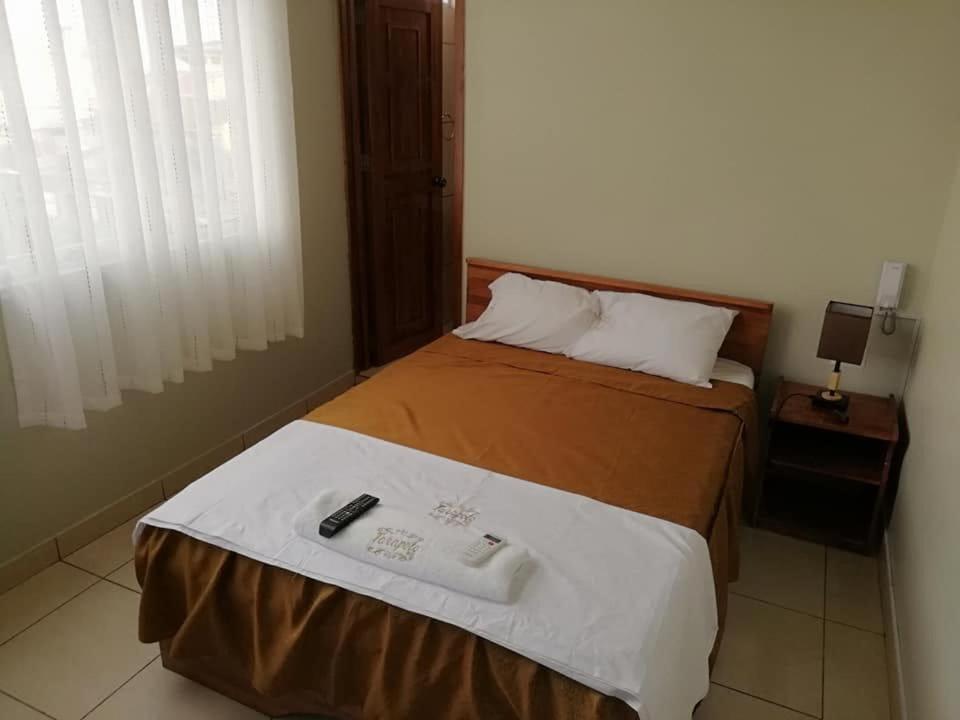 a bedroom with a bed with a remote control on it at Tarapoto Hostal *** in Iquitos