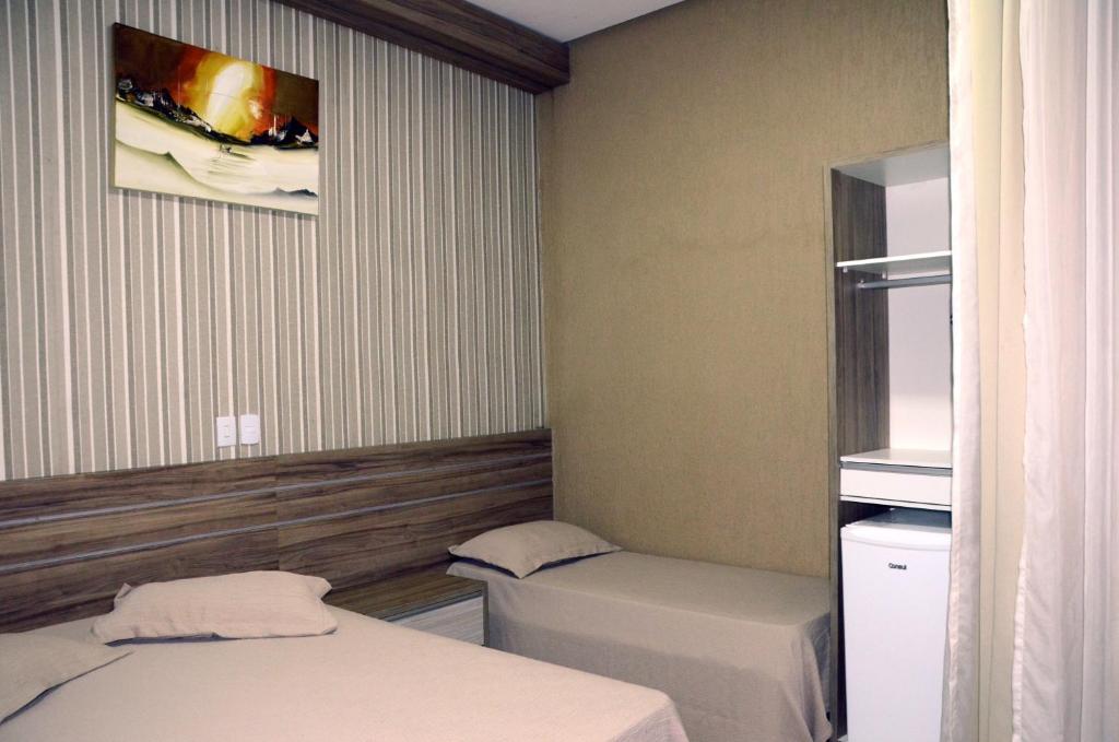 Habitación pequeña con 2 camas y una foto en la pared. en Hotel Grutta, en Bom Jesus da Lapa