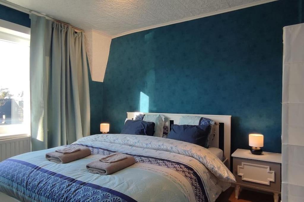 a bedroom with a large bed with blue walls at Kind -& diervriendelijk huisje in De Panne