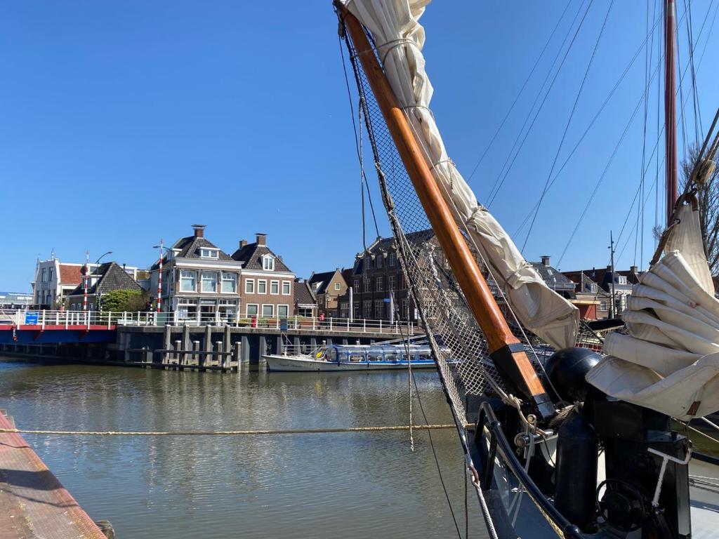 een boot is aangemeerd in een rivier met huizen bij Vakantiewoning Suderhaven in Harlingen