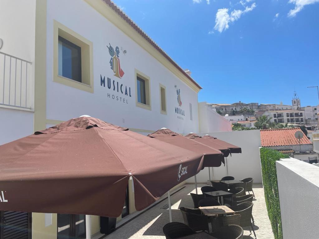 een groep parasols en stoelen voor een gebouw bij Musical Hostel in Albufeira