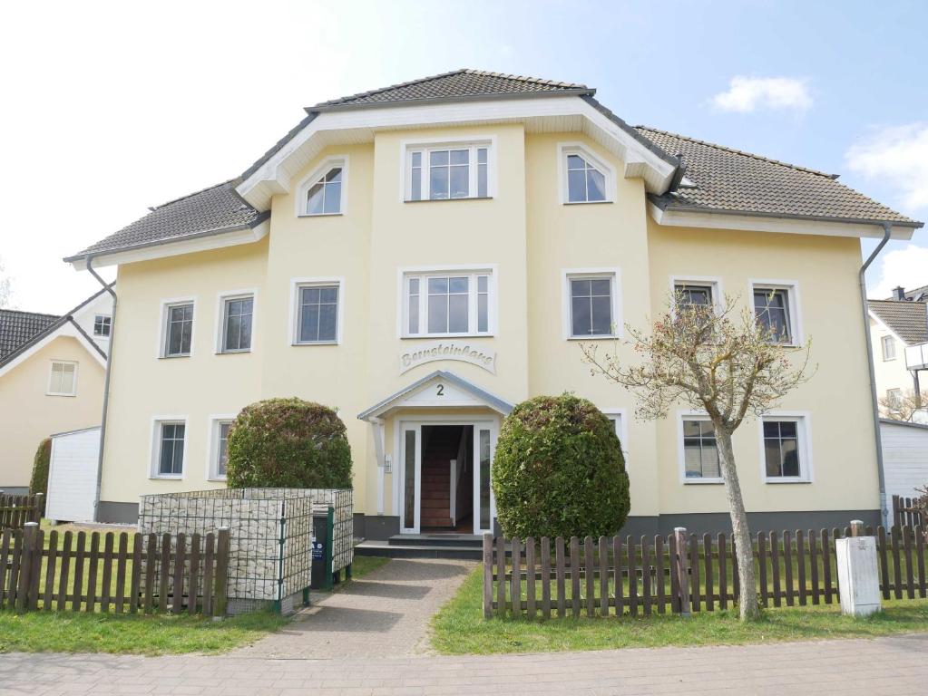 una grande casa bianca con una recinzione in legno di Bernsteinhaus Wohnung 3 mit 2 Balkonen & Kamin a Kolpinsee