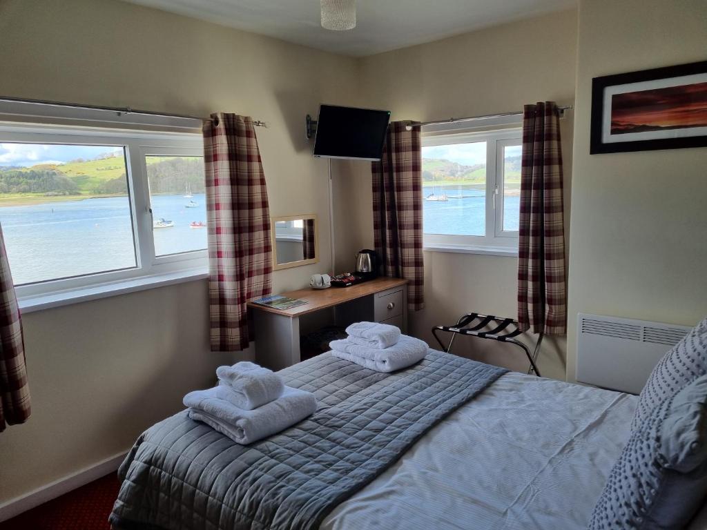 a bedroom with two towels on a bed with windows at The Anchor Hotel in Kippford