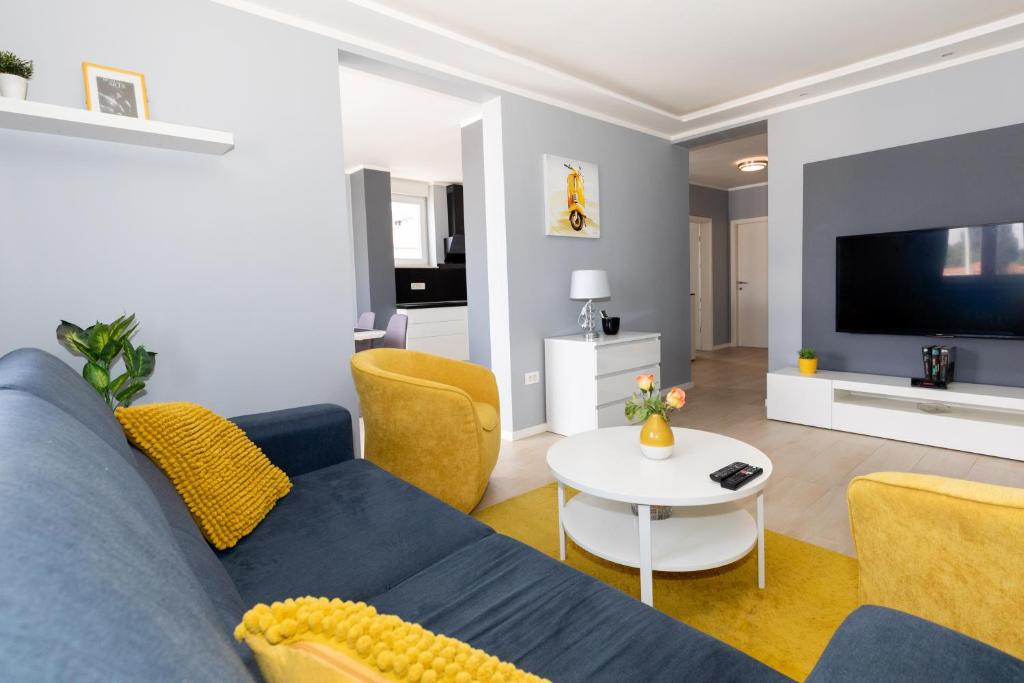 uma sala de estar com um sofá azul e uma televisão em Apartman R&B em Zadar