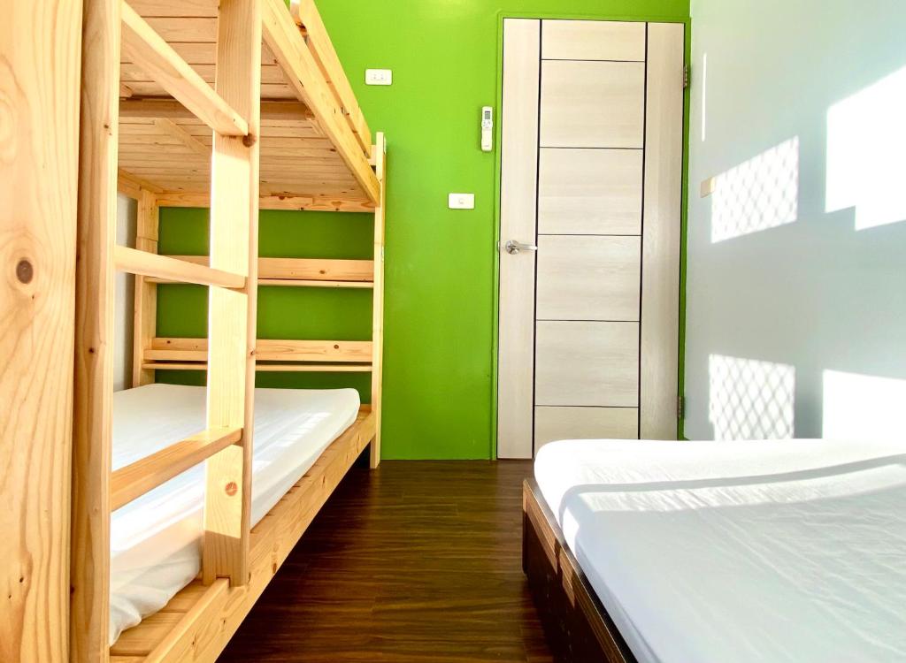 a room with two bunk beds and a green wall at 澎湖北吉光背包客民宿 Bayhouse Hostel Penghu in Magong