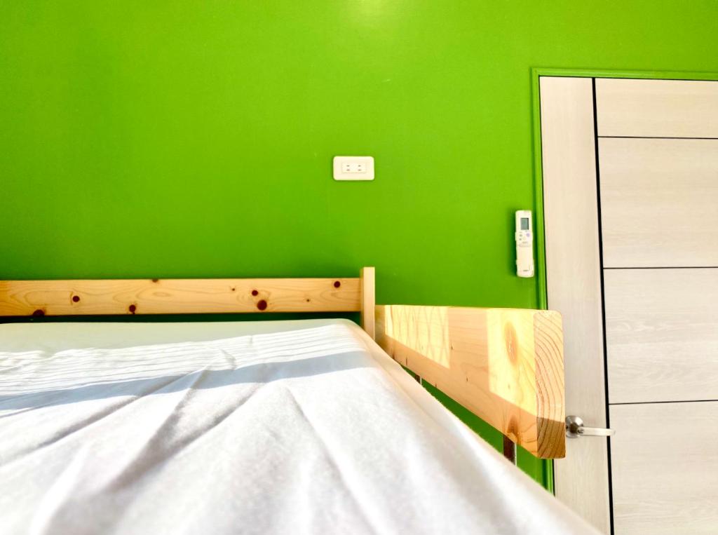 a bedroom with a green wall and a bed at 澎湖北吉光背包客民宿 Bayhouse Hostel Penghu in Magong