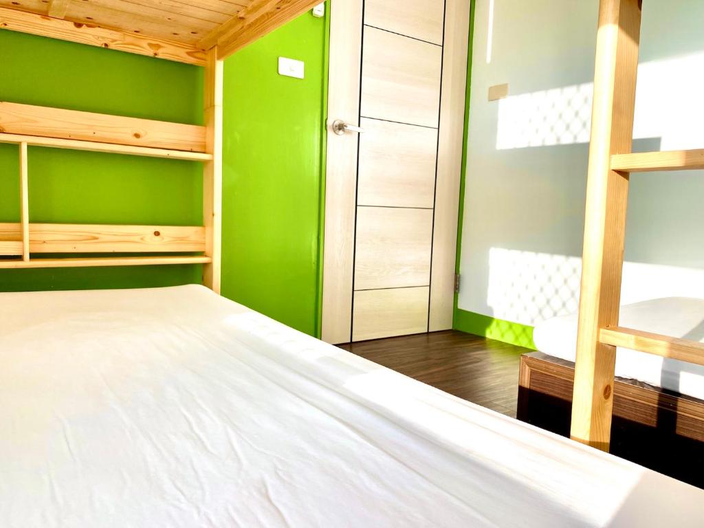 a bedroom with green walls and a white bed at 澎湖北吉光背包客民宿 Bayhouse Hostel Penghu in Magong