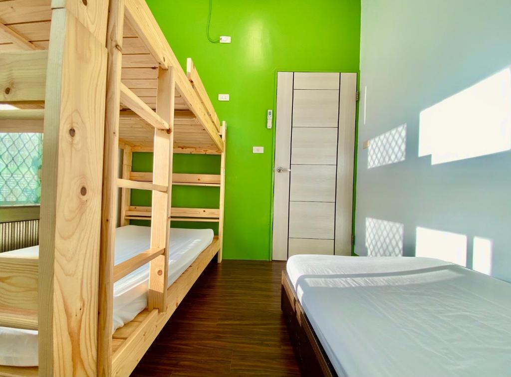 a room with two bunk beds and a green wall at 澎湖北吉光背包客民宿 Bayhouse Hostel Penghu in Magong