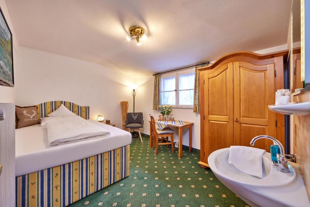 a bedroom with a bed and a sink and a desk at Gästehaus Angela in Garmisch-Partenkirchen