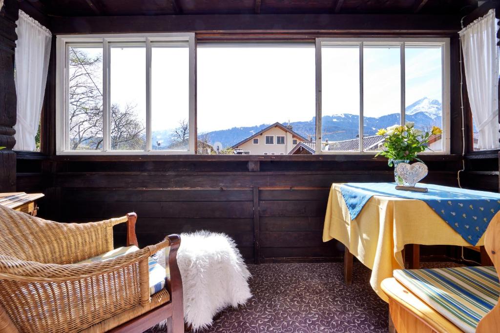 a room with a table and chairs and windows at Gästehaus Angela in Garmisch-Partenkirchen