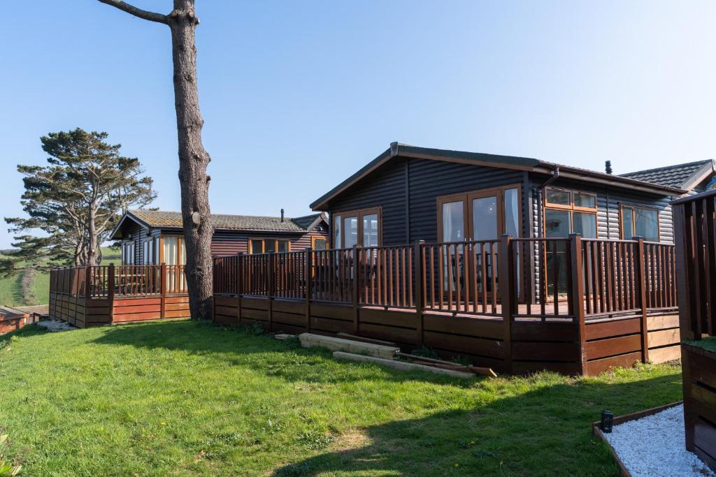 una casa con terraza y un árbol en Finest Retreats - Serendipity Lodge en Torpoint