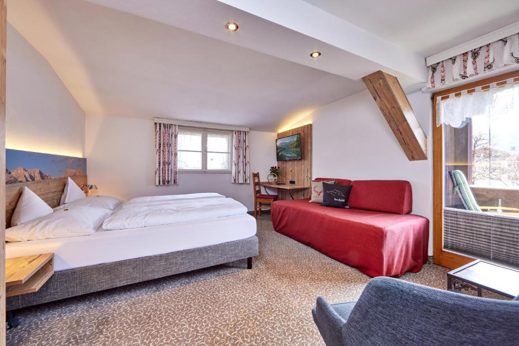 a bedroom with a bed and a red chair at Gästehaus Angela in Garmisch-Partenkirchen