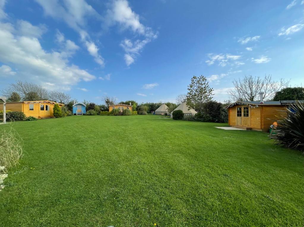 a large yard with green grass and houses at Coutts Glamping in Wadebridge