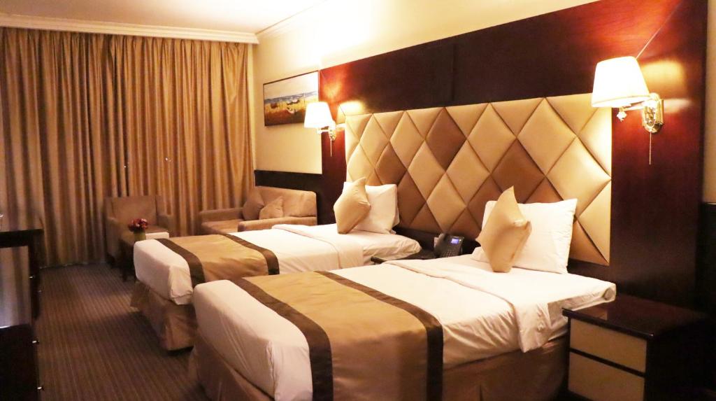 a hotel room with two beds and a chair at Gulf Inn Hotel Deira Formerly City Star Hotel in Dubai