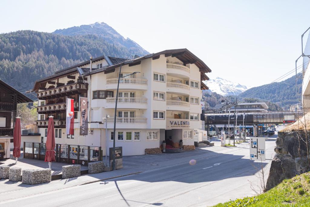 Ein großes weißes Gebäude vor dem Hintergrund der Berge in der Unterkunft Hotel Valentin in Sölden