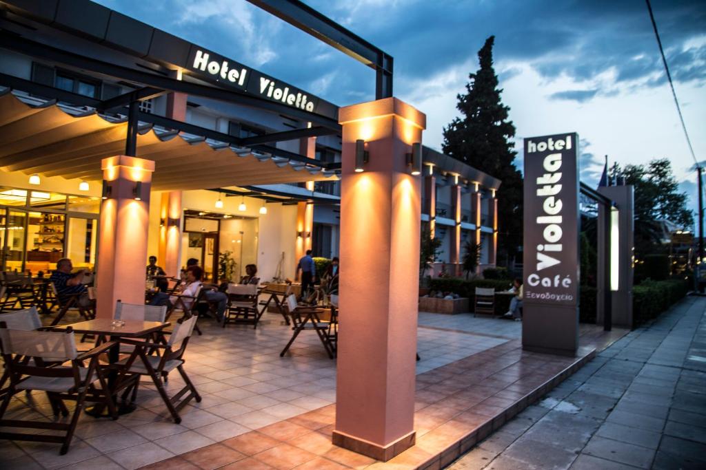 un restaurant avec des tables et des chaises en face d'un bâtiment dans l'établissement Violetta, à Kamena Vourla