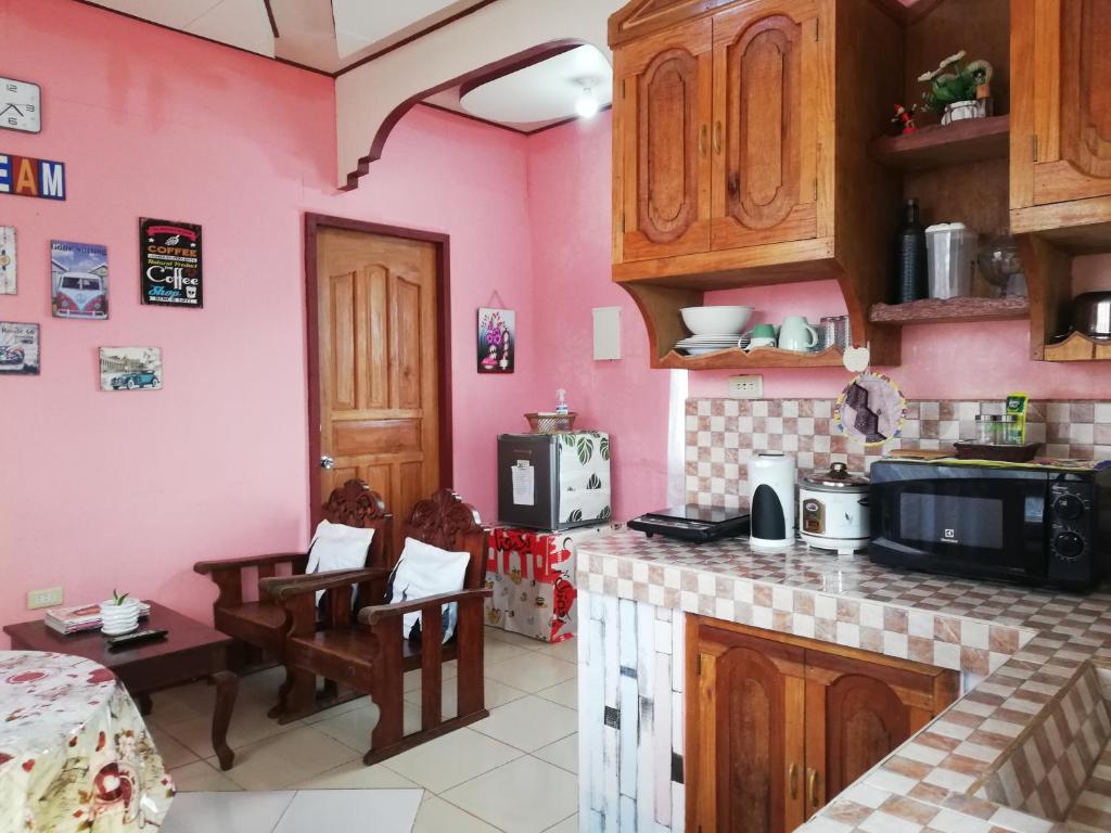 a kitchen with pink walls and wooden cabinets at Agimats Crib Palawan in Puerto Princesa City