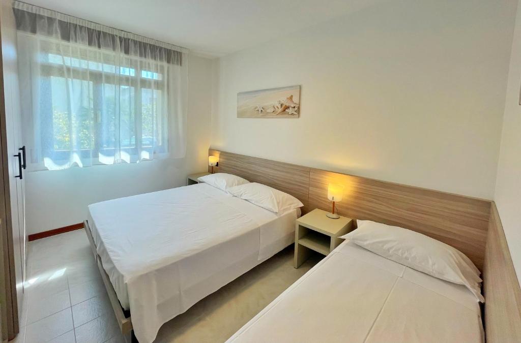 a hotel room with two beds and a window at Villa Ivona in Bibione