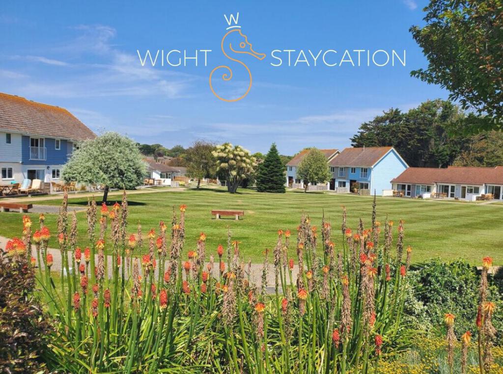 West Bay Cottages Yarmouth Isle of Wight في يارماوث: اطلاله على ساحه بها بيوت وزهور