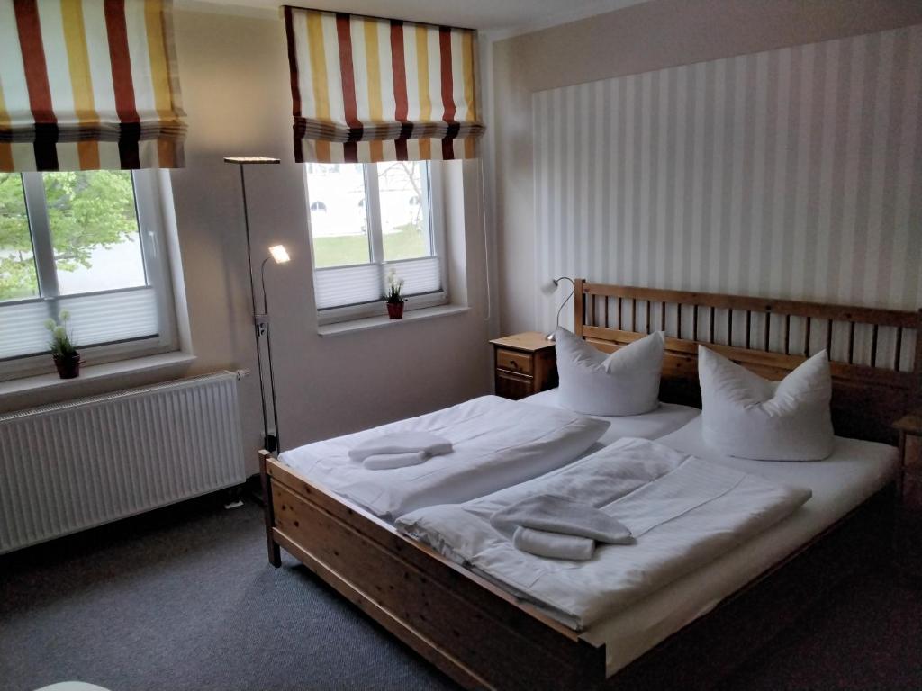 a bedroom with a bed with white sheets and pillows at Hotel am Weinbergschloss in Waren