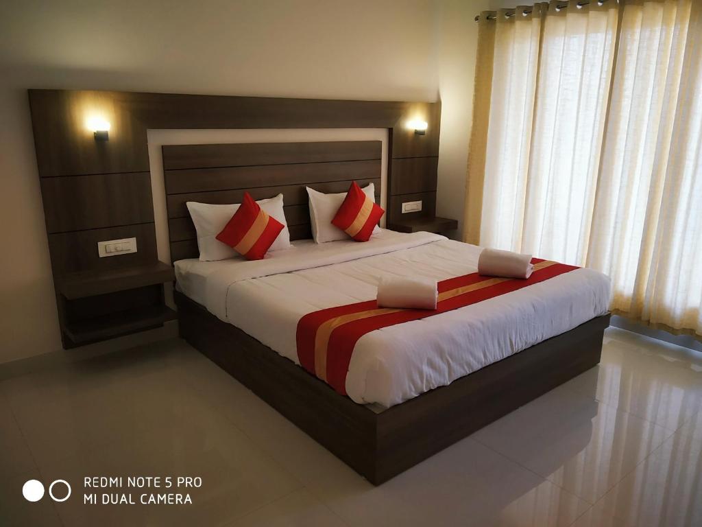 1 dormitorio con 1 cama grande con almohadas rojas y blancas en Mistica Munnar, en Anachal