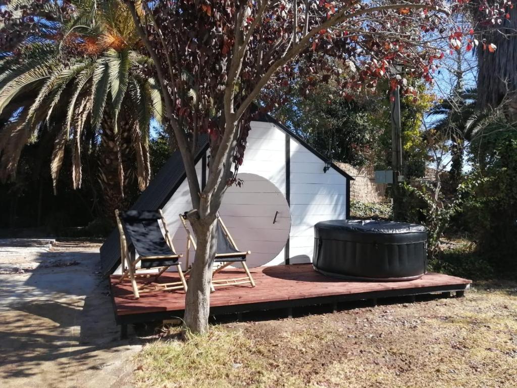 a tent with two chairs and a barrel next to a tree at Lodge Spa Melipilla in Melipilla
